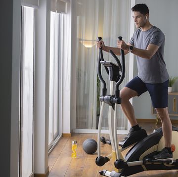 mid adult man doing exercise on cross trainer at home