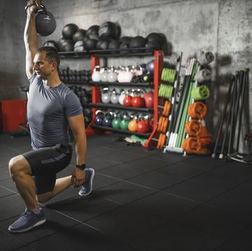 mid adult man practicing walking lunge with kettlebell during cross training in the gym