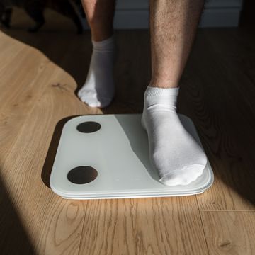 mid adult man step on weight scales at home