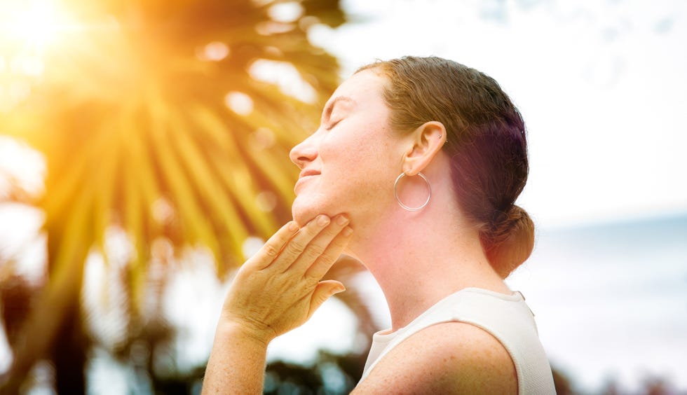 mujer protege su cara del sol