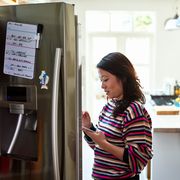 mid adult woman checking food in fridge holding tablet