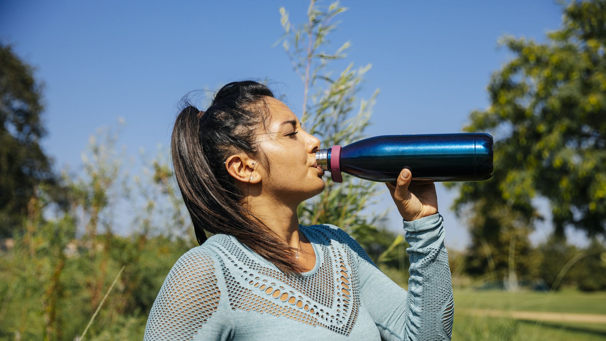https://hips.hearstapps.com/hmg-prod/images/mid-adult-woman-drinking-water-at-park-during-sunny-royalty-free-image-1646152435.jpg?crop=1xw:0.84375xh;center,top