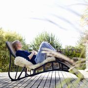 mid adult woman relaxing on lounge chair on wooden decking