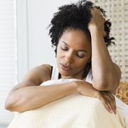 mid adult woman sitting on the bed and suffering from a headache