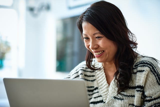 mid adult woman using laptop and smiling