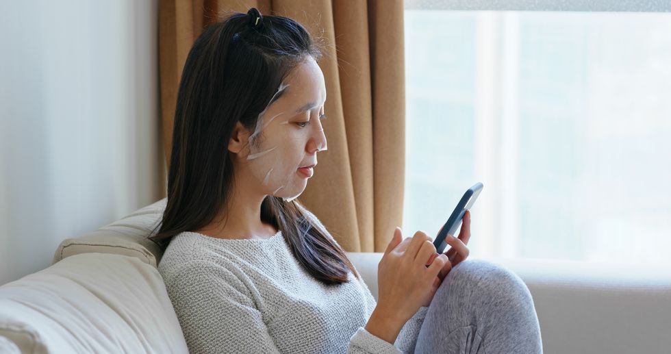 mid adult woman using mobile phone while sitting at home