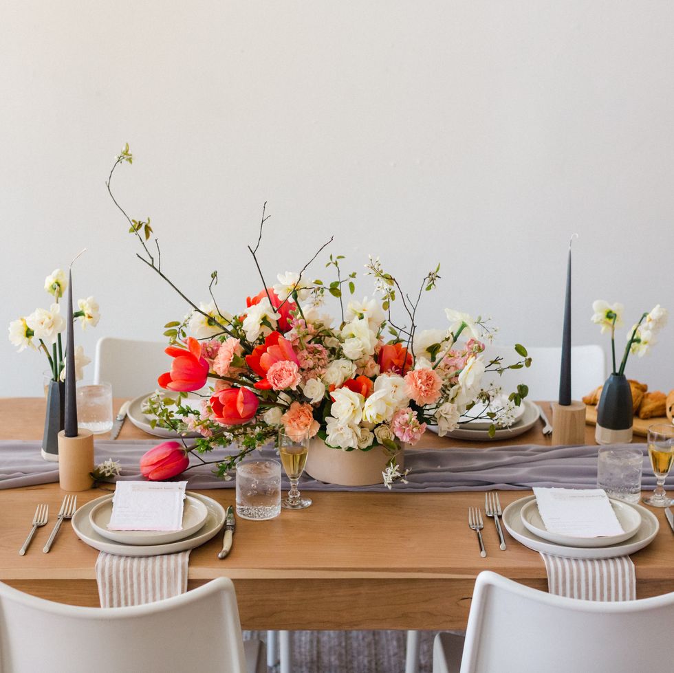 mid century modern beautiful styled pink and wedding flowers on wooden table with place setting and invite