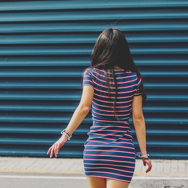 mid section brunette teenager walking away against blue wall