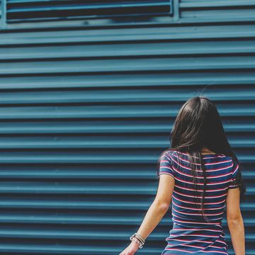 mid section brunette teenager walking away against blue wall