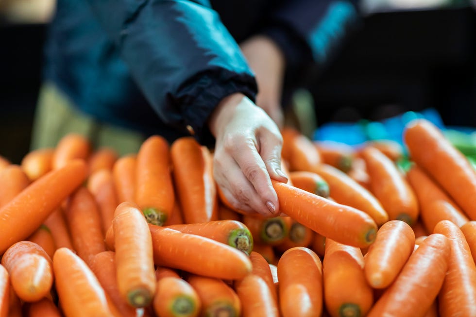 Middle-aged Asian woman buying fresh organic food in supermarket