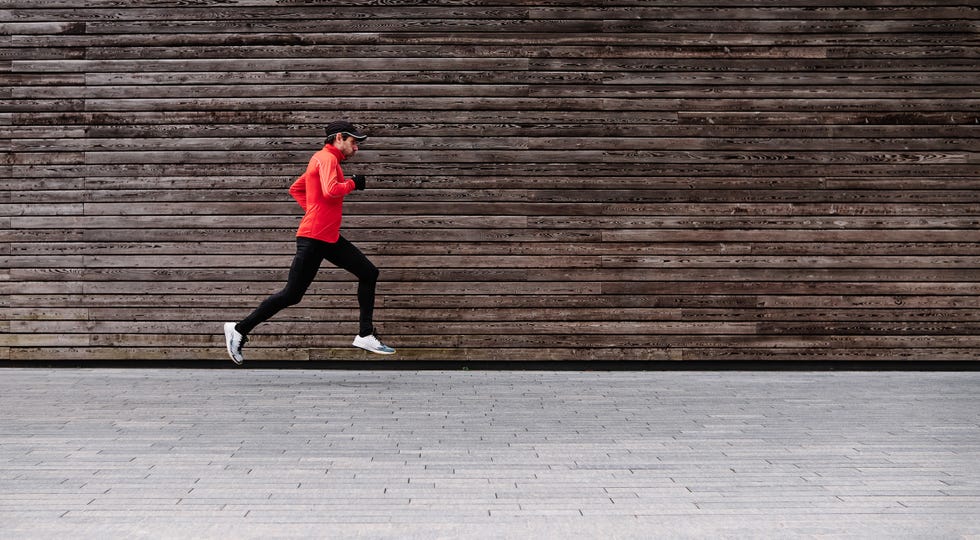 middle aged male athlete leaping against lumber wall