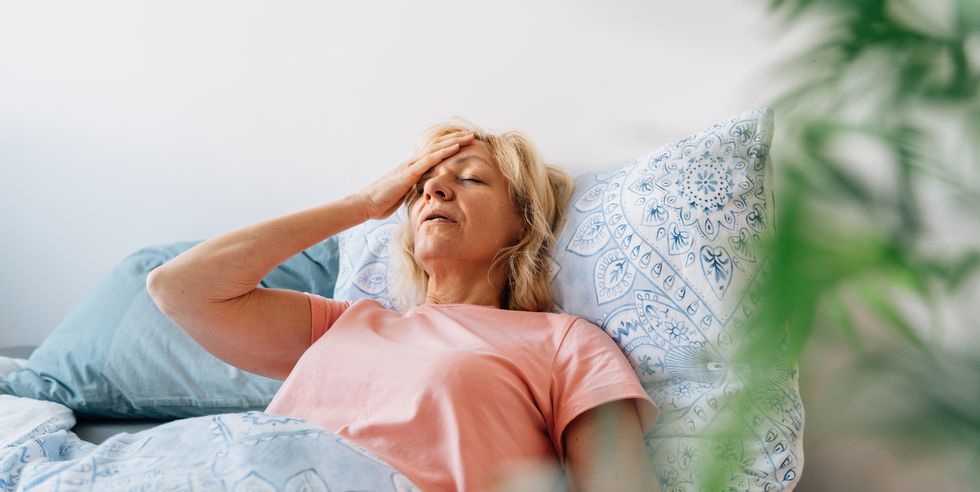 middle aged woman having hot flashes in bed