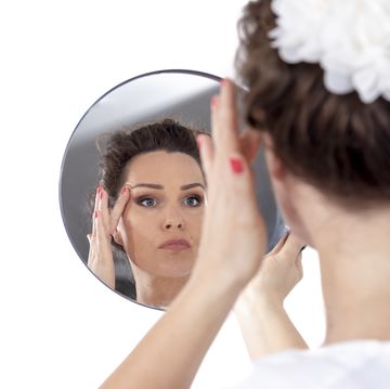 middle aged woman looks at her face in the mirror lifting sking