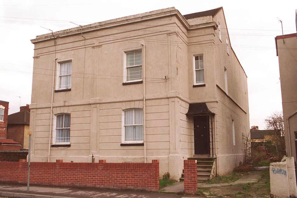 a large stucco home viewed from the street, a short brick wall divides the sidewalk from a small lawn in front