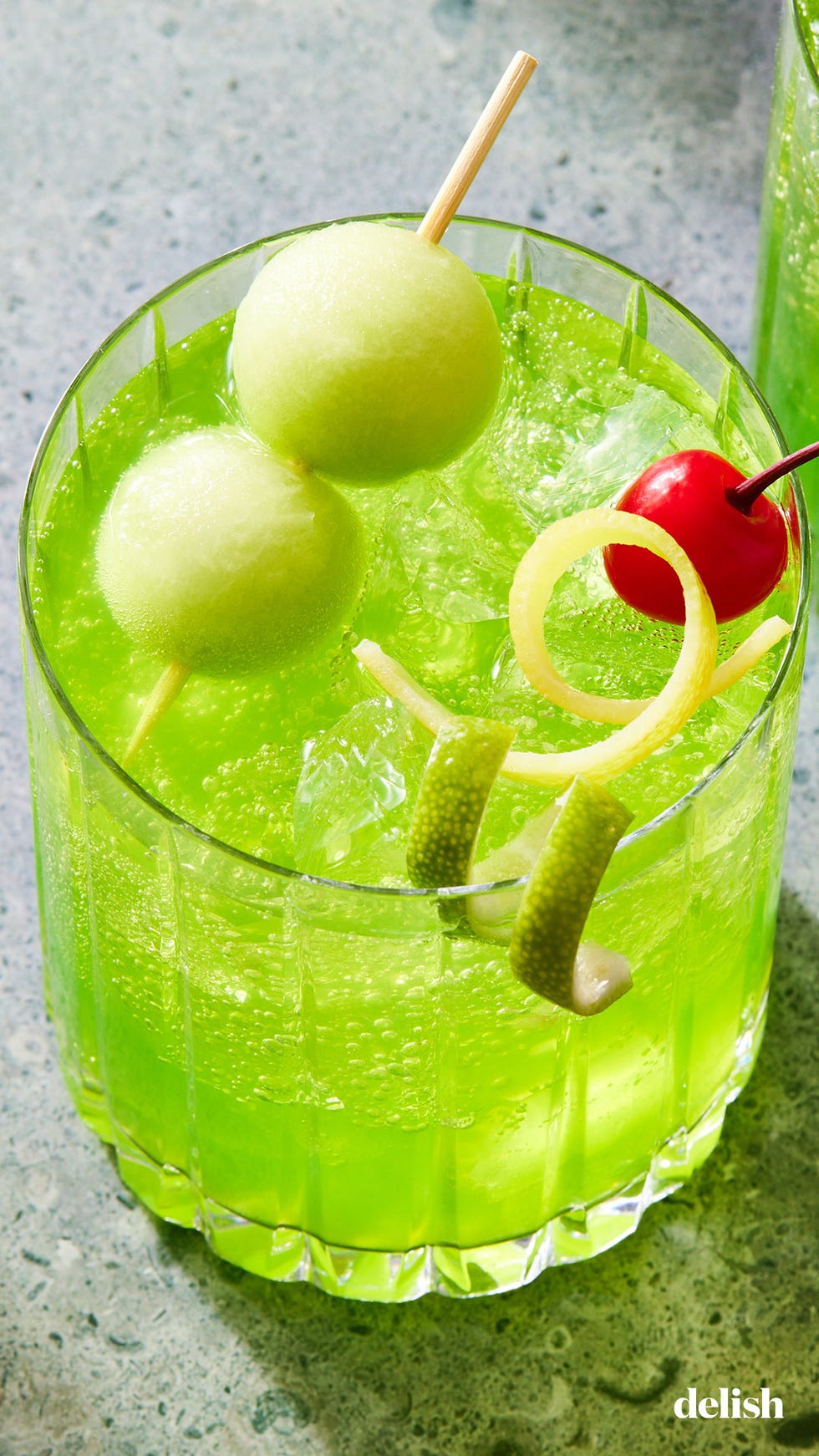 midori sour with cherry and melon ball garnish