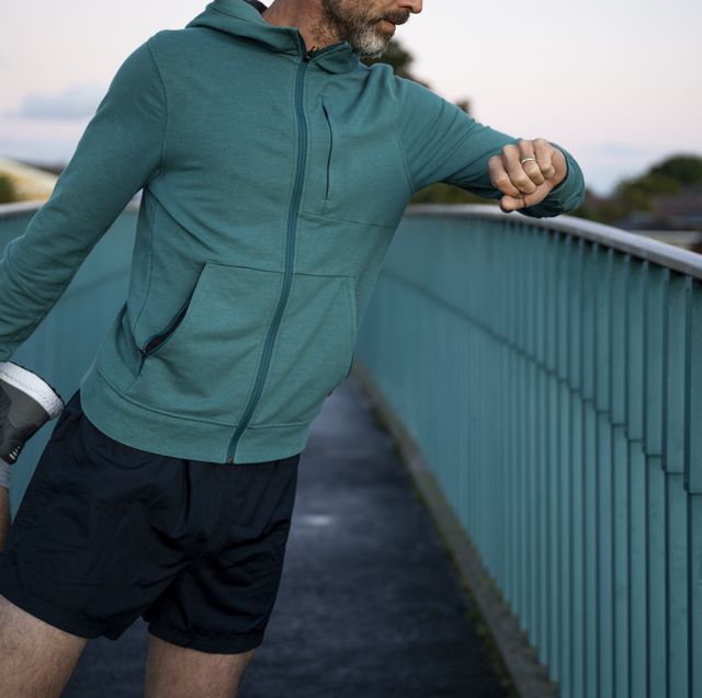 midsection man stretching leg checking watch on elevated walkway