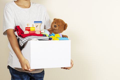 midsection of boy holding personal accessories in box against wall