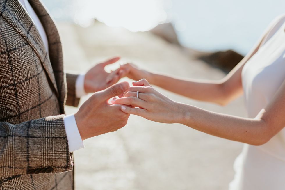 Midsection Of Bride And Groom Holding Hands While Standing Outdoors