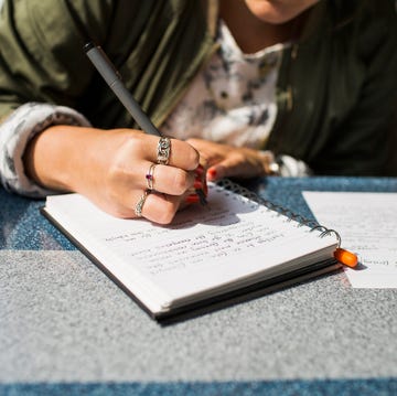 midsection of businesswoman writing on diary in train