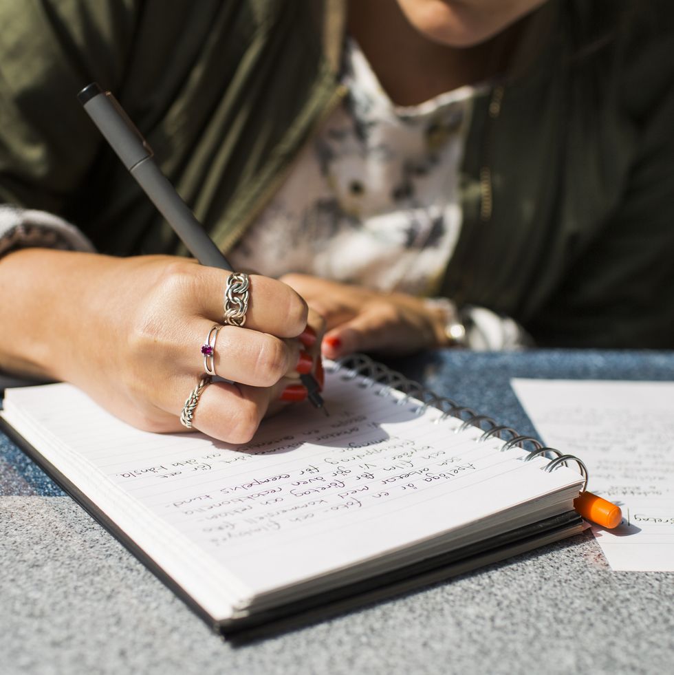 midsection of businesswoman writing on diary in train