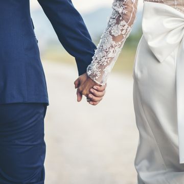 midsection of couple holding hands while walking outdoors