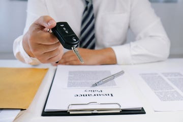 Midsection Of Insurance Agent Holding Car Key At Desk In Office