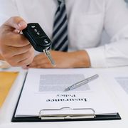Midsection Of Insurance Agent Holding Car Key At Desk In Office