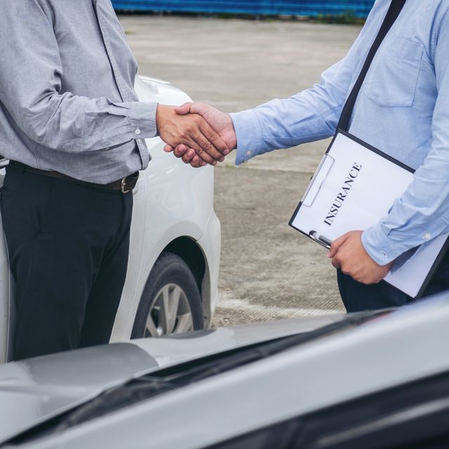 Midsection Of Insurance Agent Shaking Hand With Customer By Car