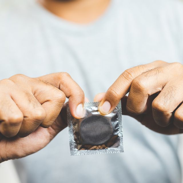 midsection of man holding condom