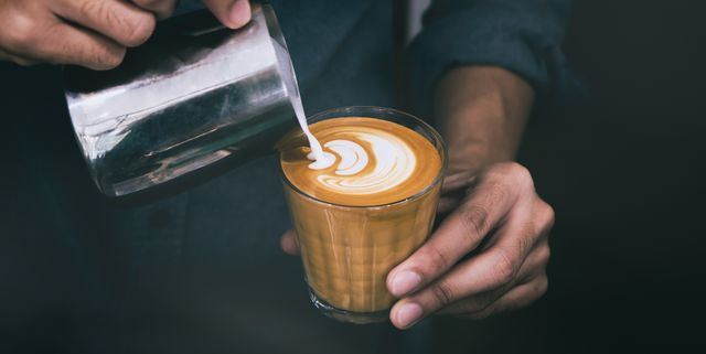midsection of man pouring milk on coffee