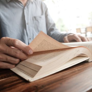 Midsection Of Man Reading Book On Table