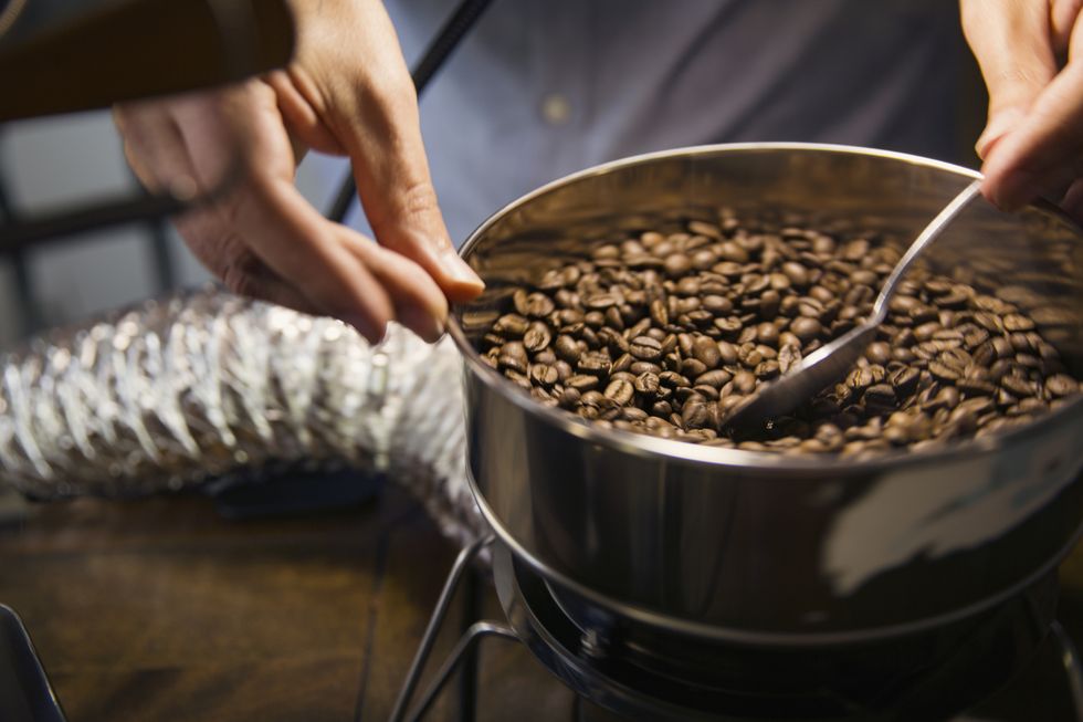 midsection of man roasting coffee beans in machinery at cafe