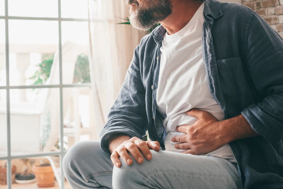 midsection of man touching stomach at home