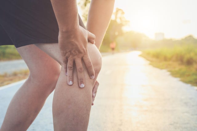 Midsection Of Man With Knee Pain Standing On Road