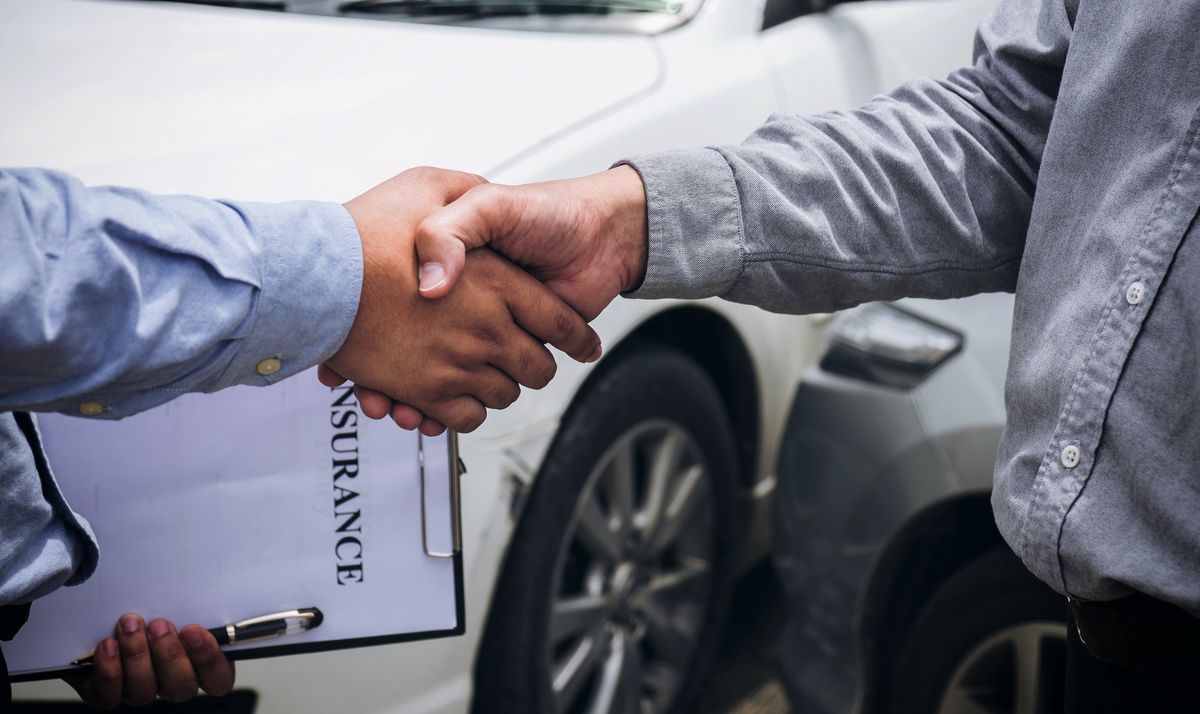 Midsection Of Men Shaking Hands After Buying Car Insurance