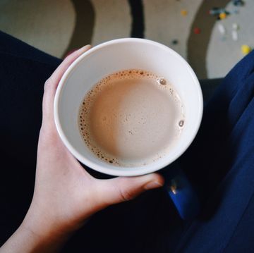 midsection of person holding chai latte at home