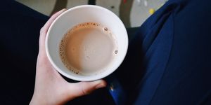 midsection of person holding chai latte at home