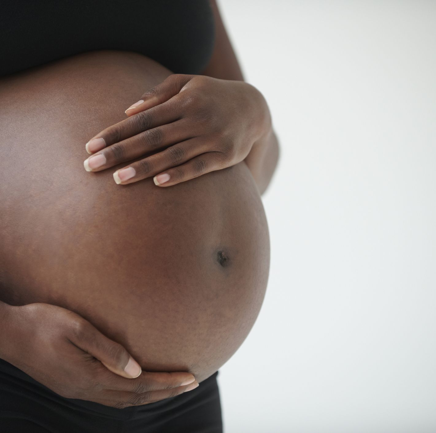 midsection of pregnant black woman holding belly
