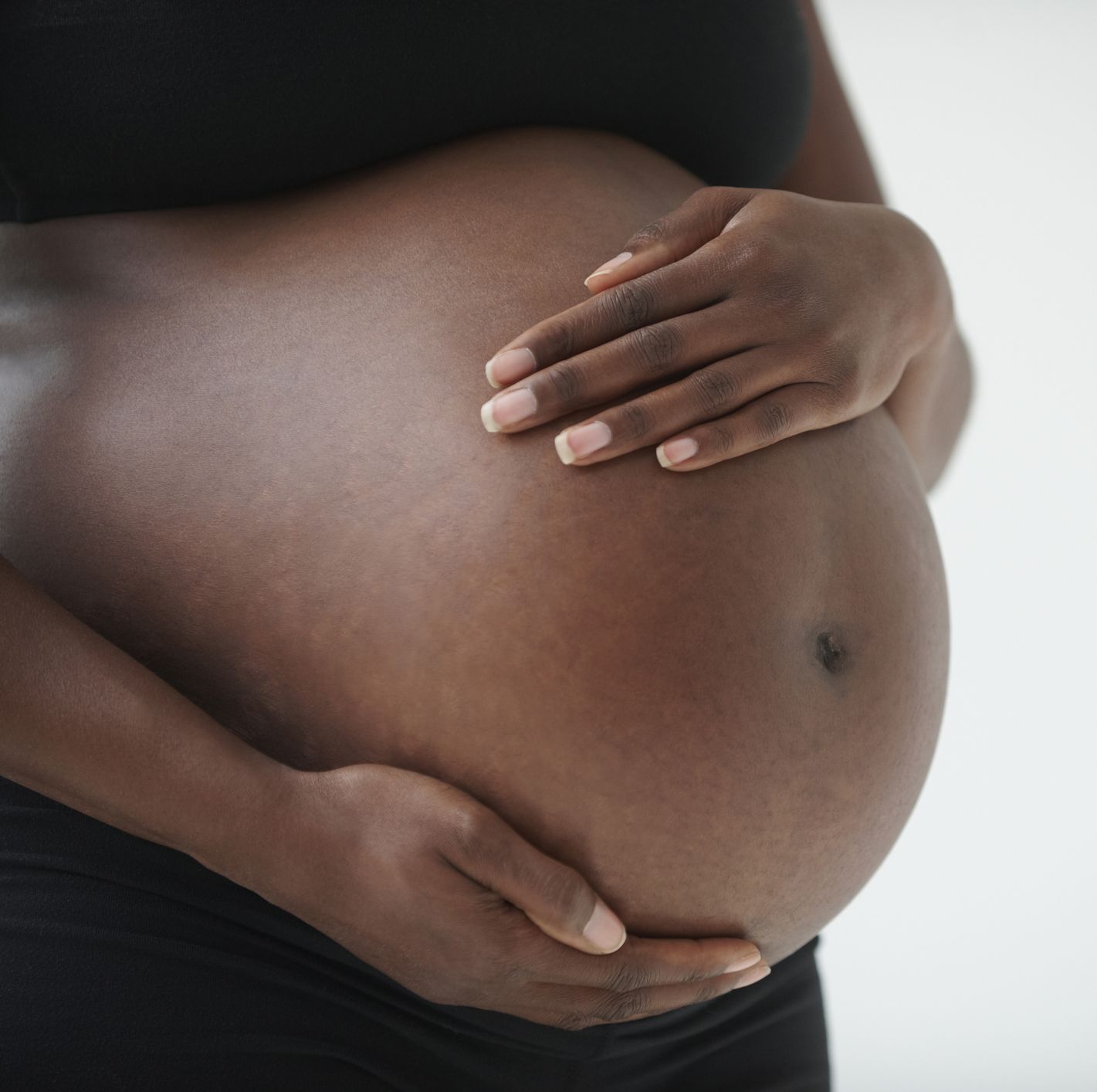 midsection of pregnant black woman holding belly