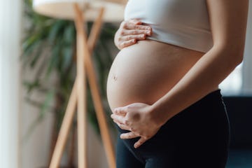 midsection of pregnant woman holding her belly