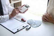 Midsection Of Real Estate Agent Showing Calculation To Customer While Sitting By Table At Office