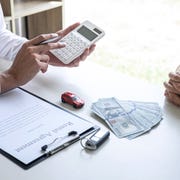 Midsection Of Real Estate Agent Showing Calculation To Customer While Sitting By Table At Office