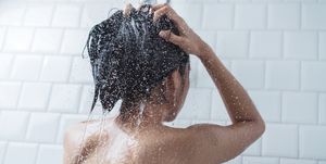 Midsection Of Topless Young Woman Taking Shower In Bathroom