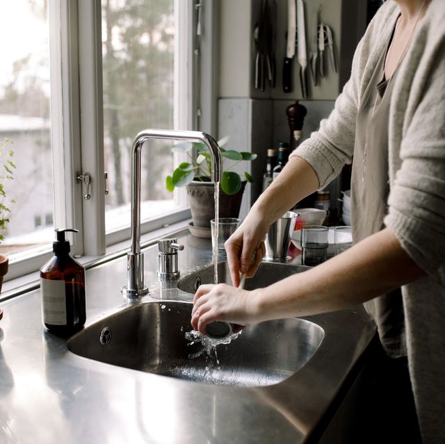 midsection of woman cleaning cup in kitchen sink at home
