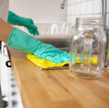 Midsection Of Woman Cleaning Kitchen Counter At Home