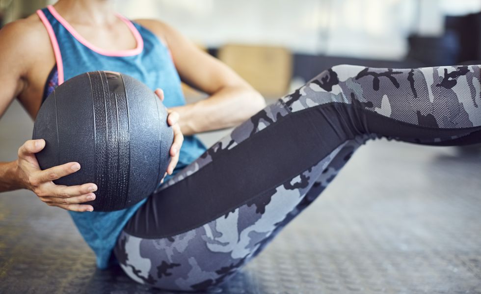 Midsection of woman exercising with medicine ball in gym