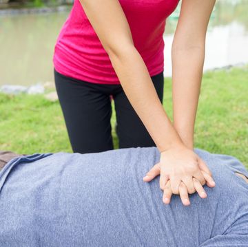 midsection of woman giving cpr to man lying in grassy field