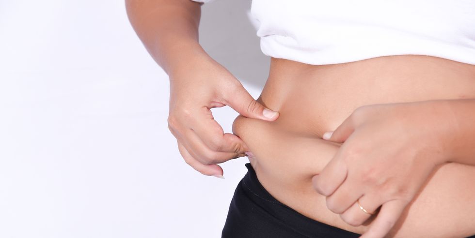 midsection of woman holding belly while standing against white background