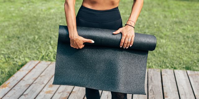 Midsection Of Woman Holding Exercise Mat While Standing Outdoors