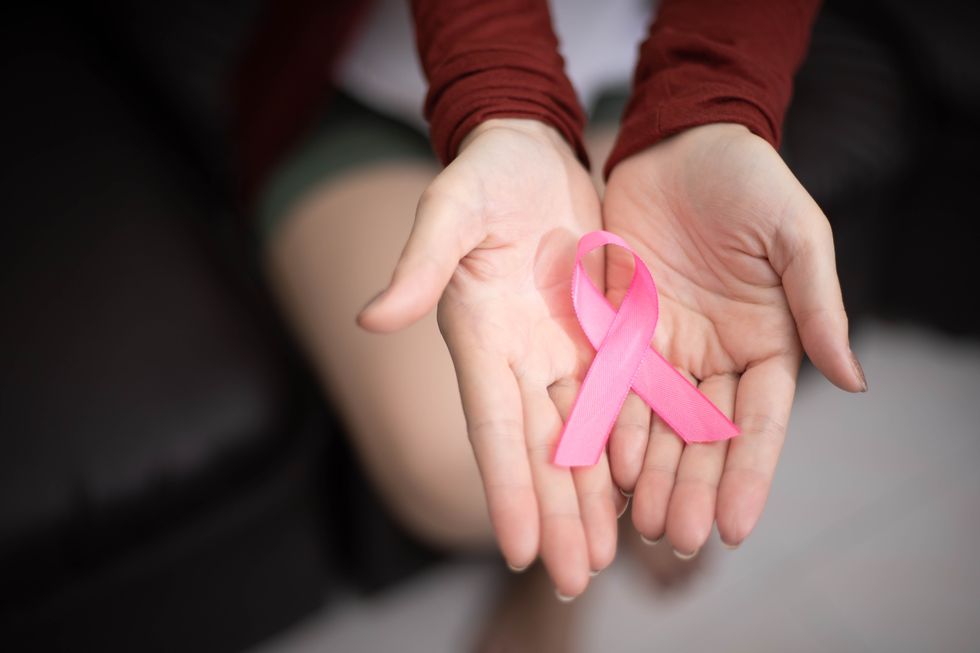 midsection of woman holding pink breast cancer awareness ribbon